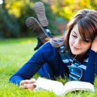 Girl reading a book in the grass