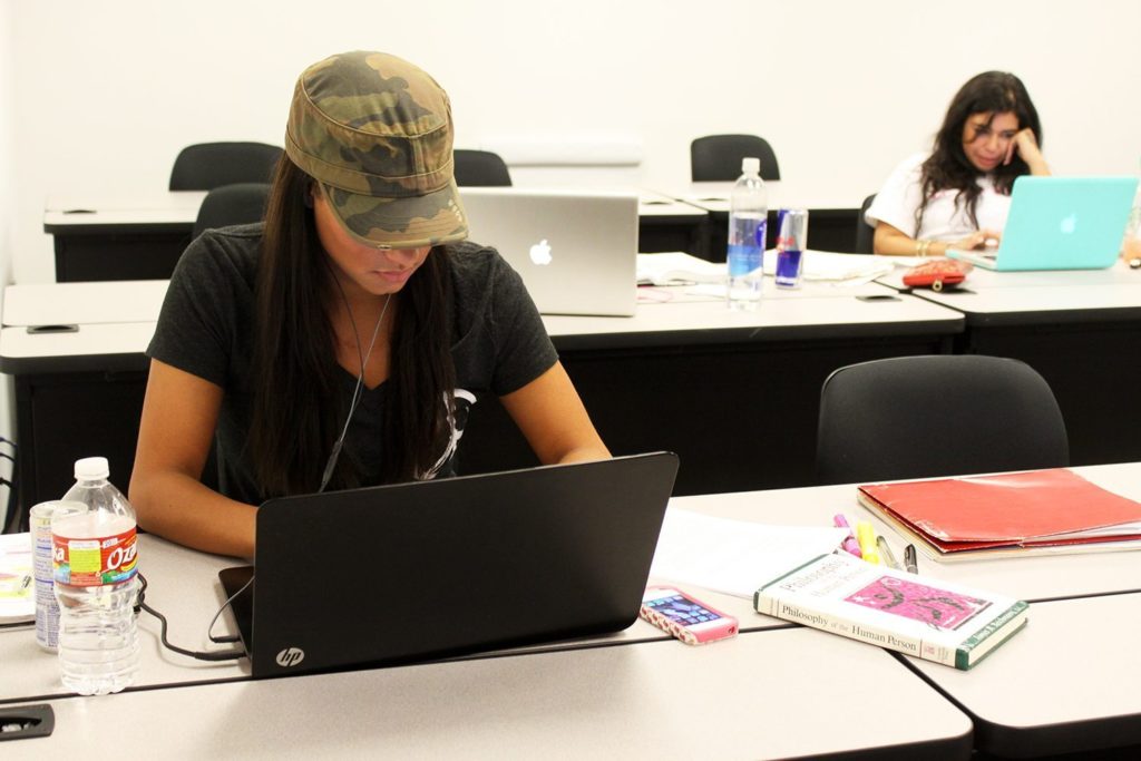 Female college students studying for finals on their laptops in a classroom at the University of St. Thomas - Houston, Texas