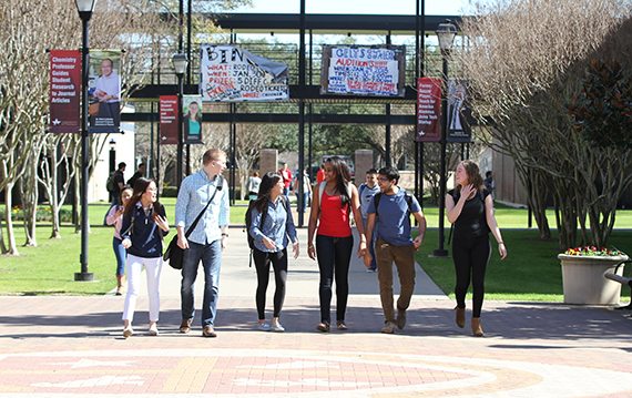 An ethnically diverse group of students walk and talk on the University of St. Thomas – Houston campus