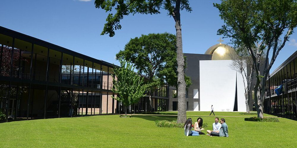 University of St. Thomas - Houston students sit on the grass in front of the Chapel of St. Basil